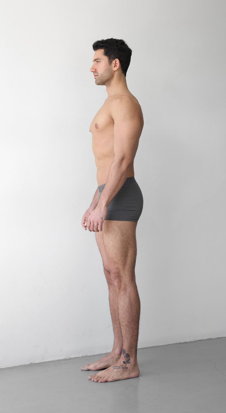 Full-body digital of a male model, side view, head to toe against a plain wall