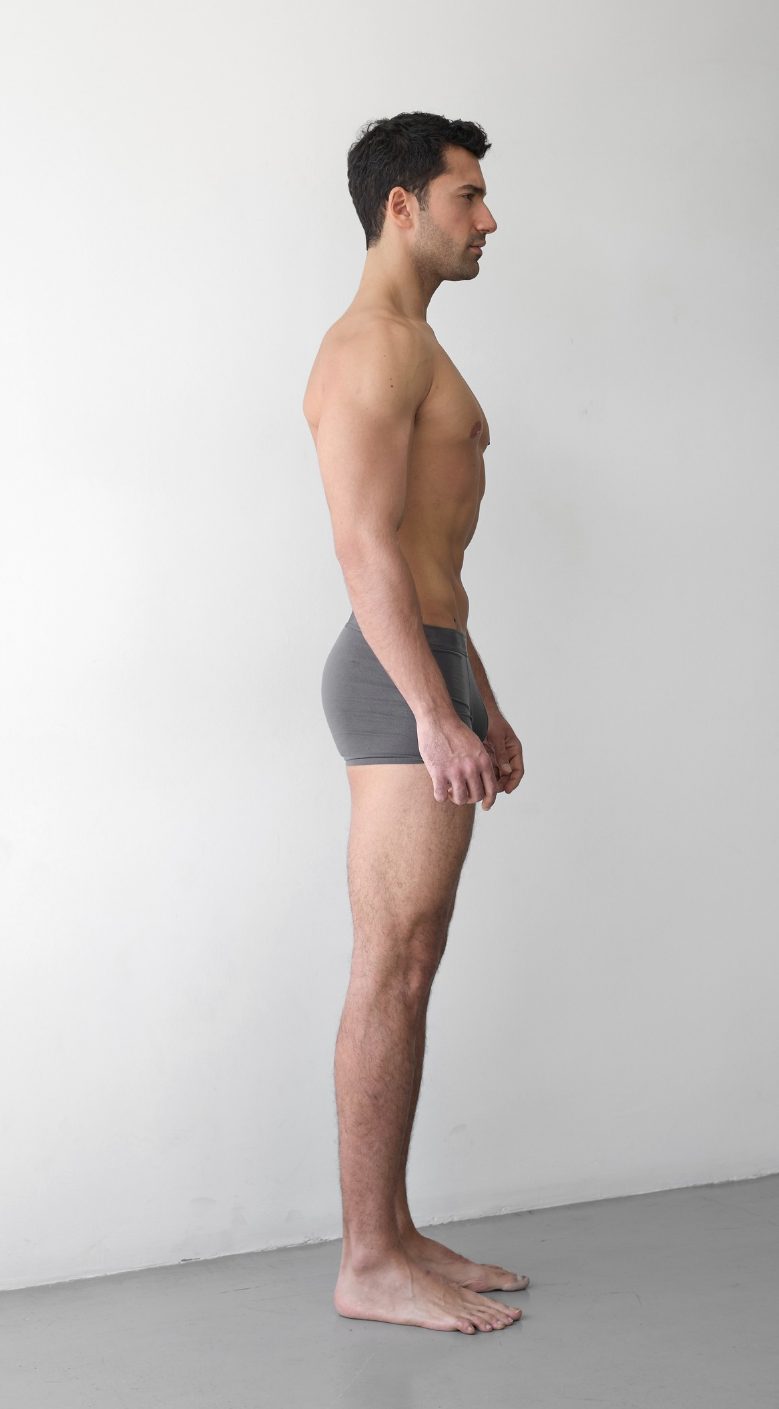Full-body digital of a male model, other side view, head to toe against a plain wall